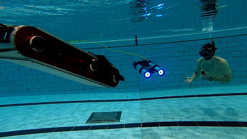 photo of two robots and a human underwater in a swimming pool